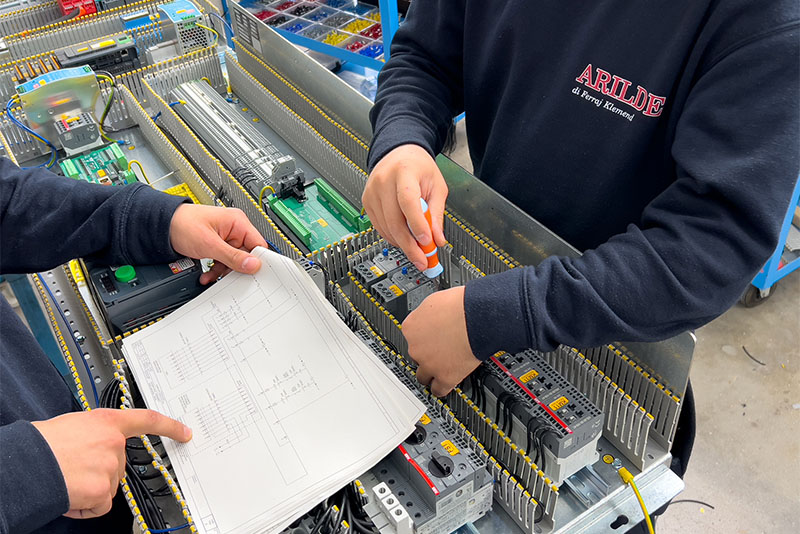 Cablatori che lavorano mentre controllano uno schema elettrico.